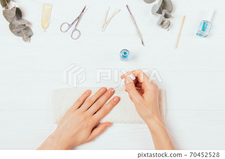 Female hands apply nail polish next to self-manicure accessories Female hands apply nail polish next to self-manicure accessories 70452528