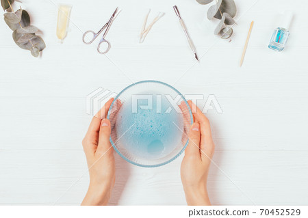 Top view woman's hands holding bowl of warm soapy water Top view woman's hands holding bowl of warm soapy water 70452529