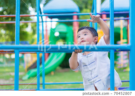 Asian boy hang the metal bar at outdoor playground. 70452807