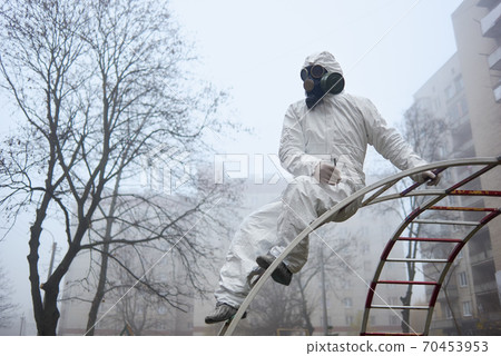 Man in protective clothing sitting on ladder on playground. Man in protective clothing sitting on ladder on playground. 70453953