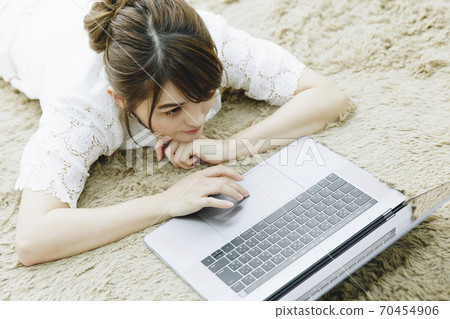 A woman lying down and watching a computer 70454906
