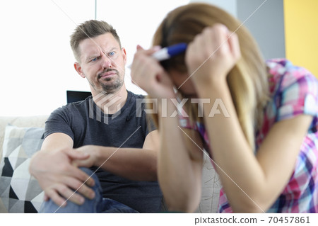 Surprised man looks at woman with her head bowed and holding pregnancy test Surprised man looks at woman with her head bowed and holding pregnancy test 70457861