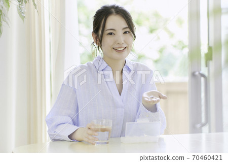 A young woman trying to take medicine in the living room A young woman trying to take medicine in the living room 70460421