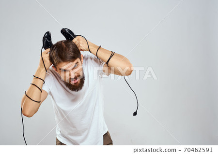 A man holds in his hands two joysticks playing leisure technology lifestyle white t-shirt A man holds in his hands two joysticks playing leisure technology lifestyle white t-shirt 70462591