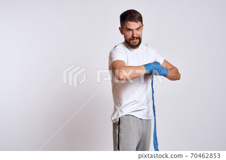 sports man in white t-shirt blue boxing bandages on his arms workout exercises sports man in white t-shirt blue boxing bandages on his arms workout exercises 70462853