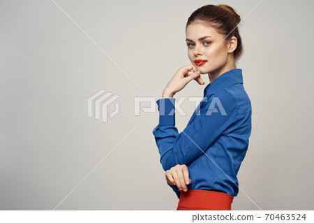 An elegant lady in a blue shirt is gesturing with her hands on a light background and a copy space close-up portrait An elegant lady in a blue shirt is gesturing with her hands on a light background and a copy space close-up portrait 70463524
