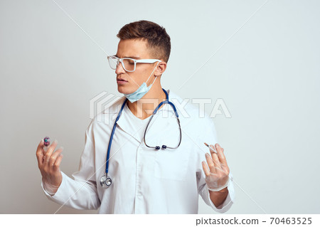 doctor in a medical gown with a stethoscope and glasses on a light background cropped view portrait doctor in a medical gown with a stethoscope and glasses on a light background cropped view portrait 70463525