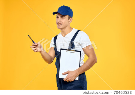 Man in working uniform documents rendering of services delivery service yellow background Man in working uniform documents rendering of services delivery service yellow background 70463528