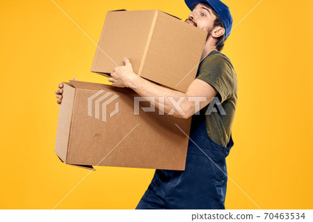 A man in a working form a box with loading tools yellow background A man in a working form a box with loading tools yellow background 70463534