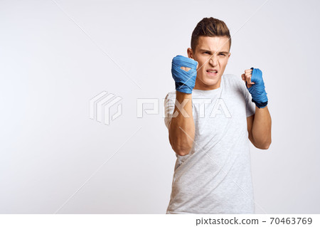 sporty male boxer in blue gloves practicing punches on a light background cropped view 70463769