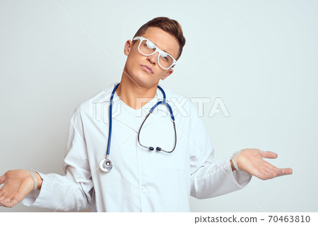 doctor in a medical gown with a stethoscope and glasses on a light background cropped view portrait 70463810
