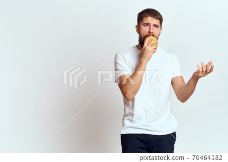 a man with an orange in a white t-shirt on a light background the diet of a brunette thick beard a man with an orange in a white t-shirt on a light background the diet of a brunette thick beard 70464182