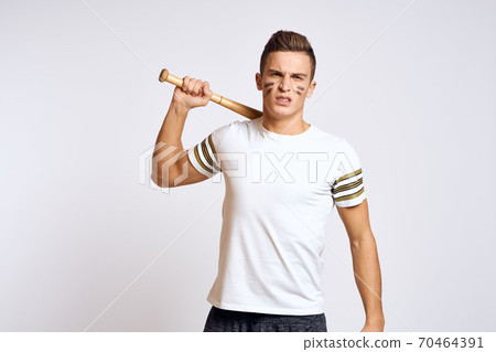 a man with a baseball bat on a light background exercises kicks sport ball model 70464391