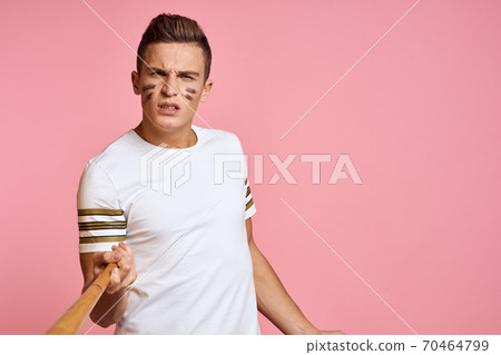 Energetic man with a bat on a pink background T-shirt face make-up black lines aggression model 70464799