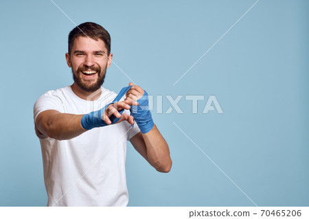 sport man in white t-shirt boxing bandages on hands blue isolated background exercise workout sport man in white t-shirt boxing bandages on hands blue isolated background exercise workout 70465206