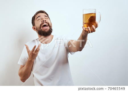 man with a mug of beer in his hands and a white t-shirt light background mustache beard emotions model man with a mug of beer in his hands and a white t-shirt light background mustache beard emotions model 70465549