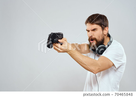 Man with gamepad headphones playing leisure technology white t-shirt light background Man with gamepad headphones playing leisure technology white t-shirt light background 70465848