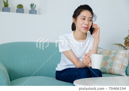 Beautiful woman drinking coffee in living room and talking on mobile phone Beautiful woman drinking coffee in living room and talking on mobile phone 70466194