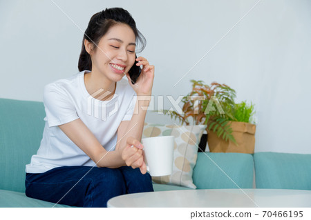 Beautiful woman drinking coffee in living room and talking on mobile phone Beautiful woman drinking coffee in living room and talking on mobile phone 70466195