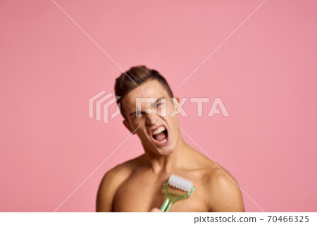 Handsome man with massager in hand on isolated pink background cropped view clean skin Handsome man with massager in hand on isolated pink background cropped view clean skin 70466325