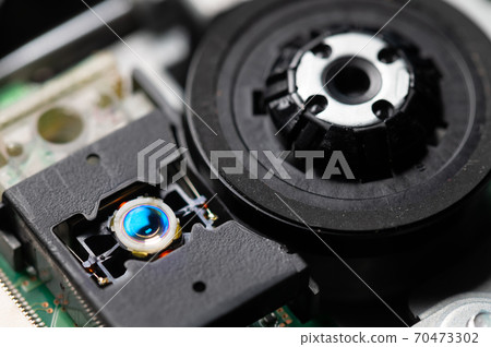 Macro close-up of a DVD drive head with a laser lens on the background of microcircuits. Electronics background 70473302