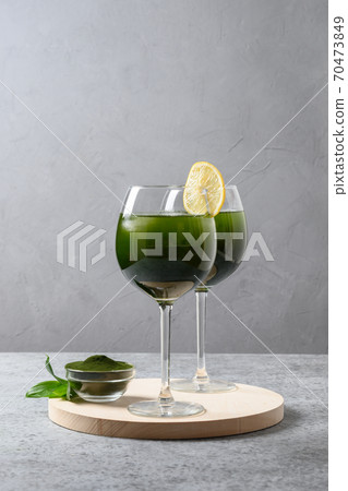 Two chlorella beverage with lemon in glass on gray 70473849