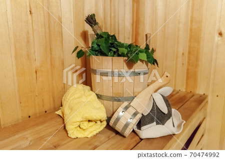 Interior details Finnish sauna steam room bathhouse with traditional sauna accessories basin birch broom scoop felt hat towel 70474992