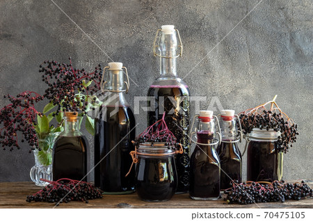 Bottles of black elder syrup with fresh elderberries Bottles of black elder syrup with fresh elderberries 70475105