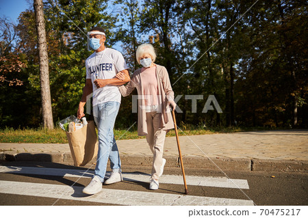 Crossing the street after doing shopping in quarantine 70475217