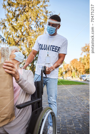 Reliable specialist walking with elderly woman in quarantine Reliable specialist walking with elderly woman in quarantine 70475257