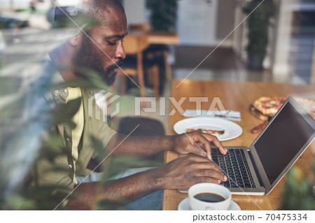 Handsome Afro American man behind glass working on laptop Handsome Afro American man behind glass working on laptop 70475334