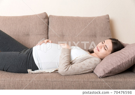 Pregnant woman with painful belly on sofa at home Pregnant woman with painful belly on sofa at home 70476598