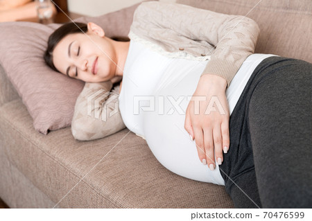 Pregnant woman relaxing at home on sofa Pregnant woman relaxing at home on sofa 70476599