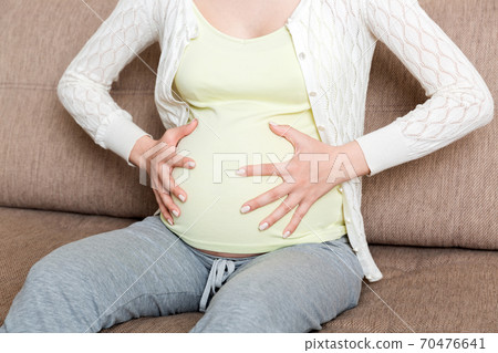 Pregnant woman with painful belly on sofa at home Pregnant woman with painful belly on sofa at home 70476641