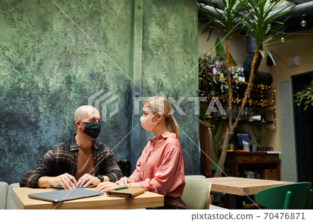 Couple in masks sitting in cafe Couple in masks sitting in cafe 70476871