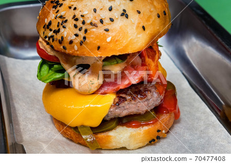 Close up tasty burger with different filling served on tray Close up tasty burger with different filling served on tray 70477408