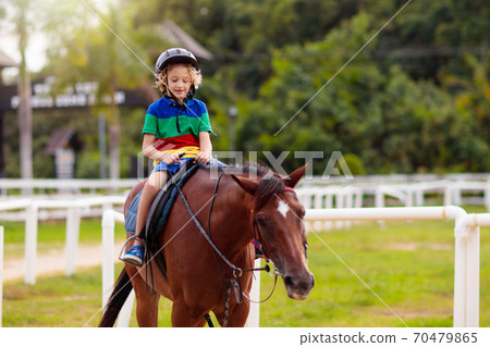 Kids ride horse. Child on pony. Horseback riding. 70479865