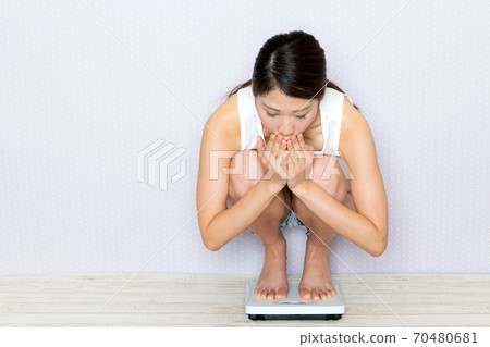 一個測量體重的女人。 一個測量體重的女人。 70480681