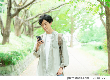 Young man walking in the green [smartphone] 70481779