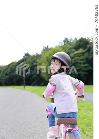 Girl practicing by taking training wheels on a bicycle 70482262