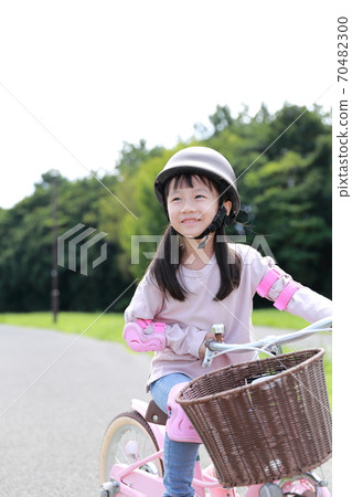 Girl practicing by taking training wheels on a bicycle 70482300