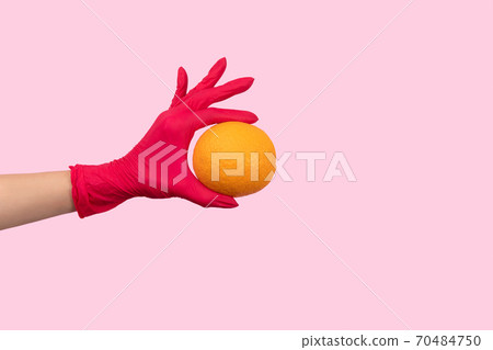 Womans hand in a pink glove holding orange Womans hand in a pink glove holding orange 70484750