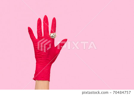 Womans hand in a rubber glove with golden ring on pink background Womans hand in a rubber glove with golden ring on pink background 70484757