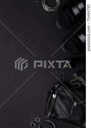 Flat lay top view bag with accessories and footwear on black background 70484795