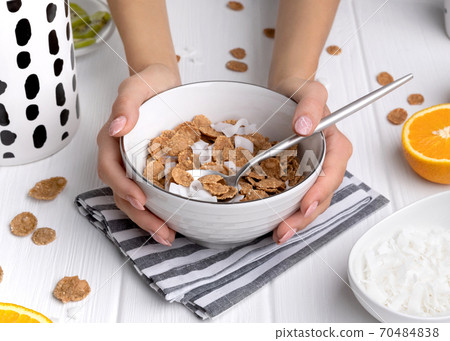 Multigrain flakes with orange and kiwi fruits and coconut in bowl 70484838