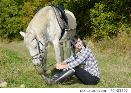 Portrait of a pretty young woman with white horse 70485202