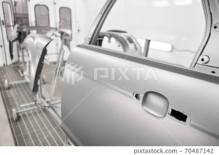 Various parts of the car on the stands for painting. Garage painting car service. Repairing car body work after the accident by working sanding primer before painting. 70487142