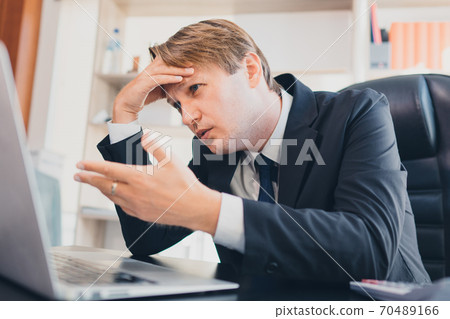 Depressed stress Caucasian businessman touch his forehead while looking at the laptop nearly cry and upset, concept failure of the business, upset stressed businessman, frustration business concept 70489166