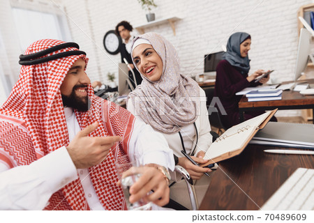 Arab man smiles while speaks with woman at work. Arab man smiles while speaks with woman at work. 70489609