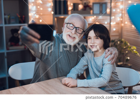 Grandfather smiles and takes selfie with grandson Grandfather smiles and takes selfie with grandson 70489676